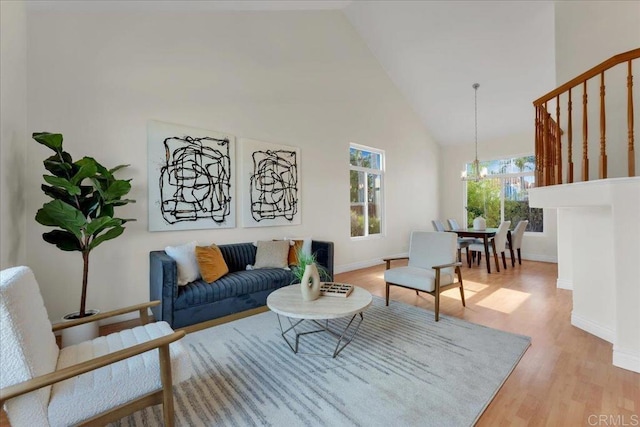 living room featuring an inviting chandelier, high vaulted ceiling, and light hardwood / wood-style floors