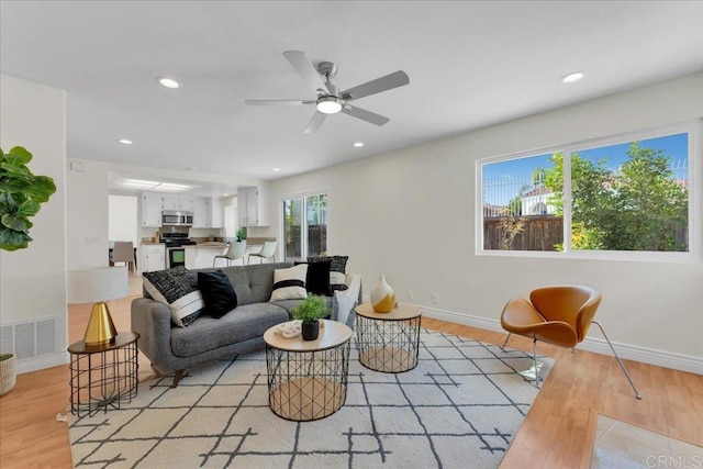 living room with light hardwood / wood-style flooring and ceiling fan