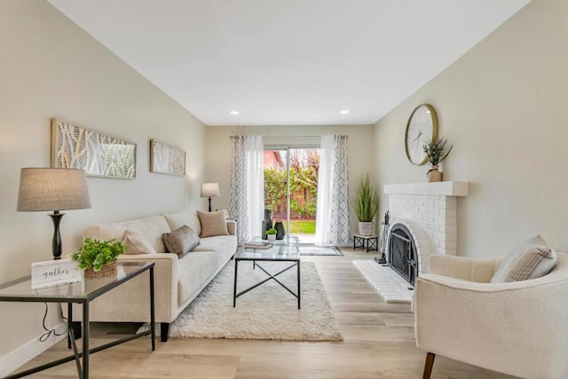 living room with a brick fireplace and light wood-type flooring