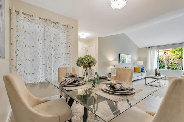 dining area with hardwood / wood-style floors and vaulted ceiling