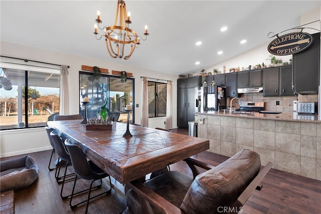 dining space with lofted ceiling, sink, a notable chandelier, and dark hardwood / wood-style flooring