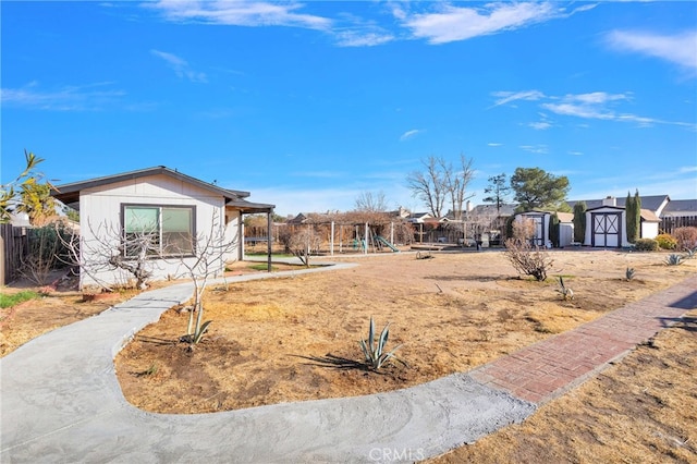 view of front of property featuring a playground and a shed