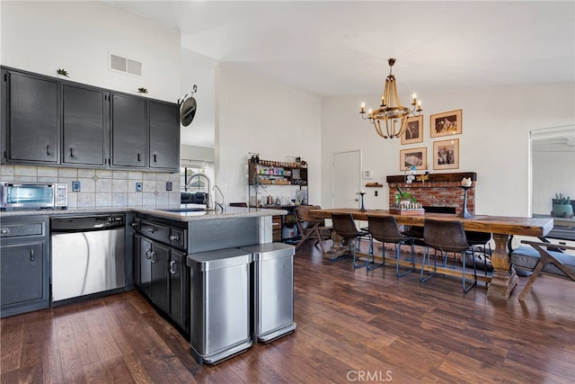 kitchen with sink, dark wood-type flooring, dishwasher, hanging light fixtures, and kitchen peninsula