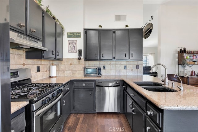 kitchen featuring light stone counters, sink, kitchen peninsula, and appliances with stainless steel finishes