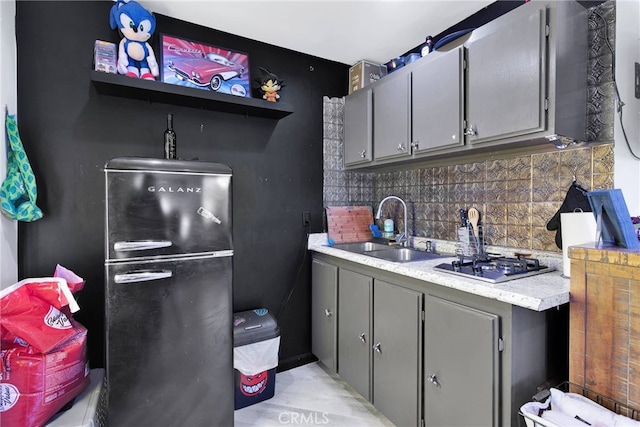 kitchen with tasteful backsplash, sink, gray cabinetry, and black fridge