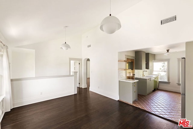 unfurnished living room with sink, dark hardwood / wood-style flooring, and high vaulted ceiling