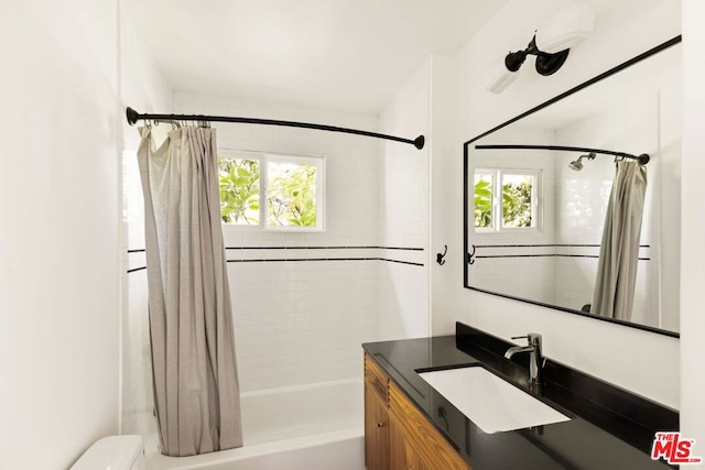 full bathroom with shower / bath combo, a healthy amount of sunlight, vanity, and toilet