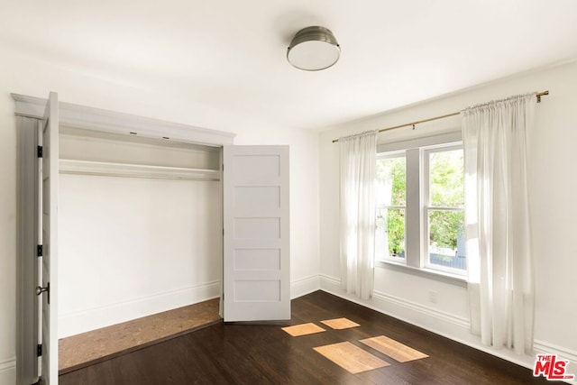 unfurnished bedroom with dark hardwood / wood-style floors and a closet