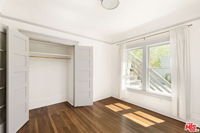 unfurnished bedroom with a closet and dark hardwood / wood-style floors