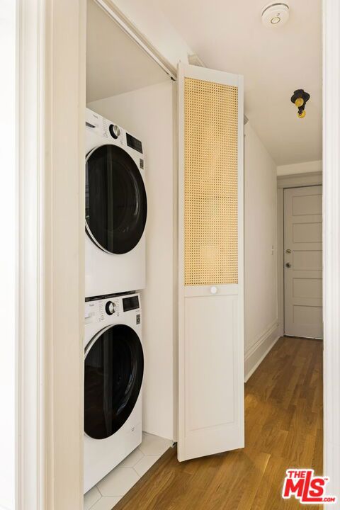 washroom featuring stacked washer and clothes dryer and light hardwood / wood-style floors