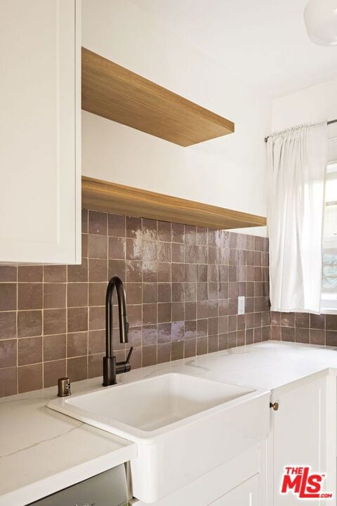 kitchen with white cabinetry, sink, and backsplash