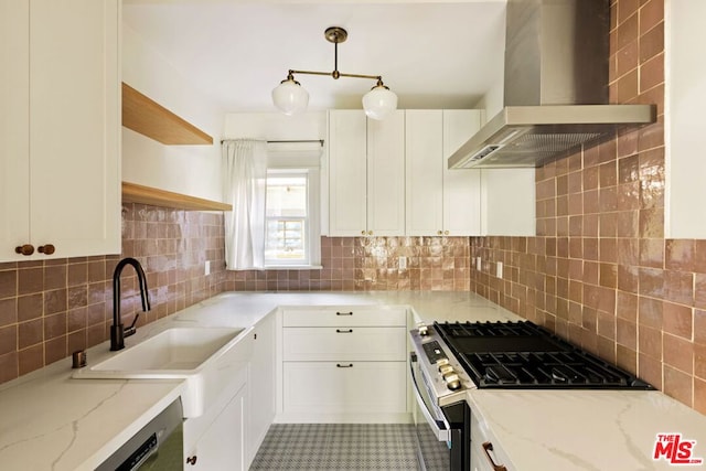 kitchen featuring white cabinetry, light stone countertops, stainless steel range with gas cooktop, and wall chimney range hood