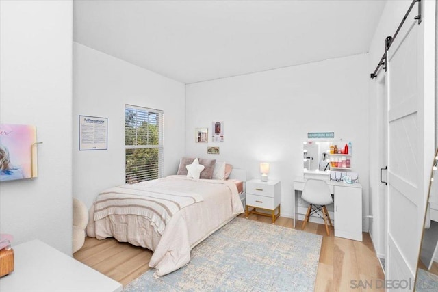 bedroom with light hardwood / wood-style floors and a barn door