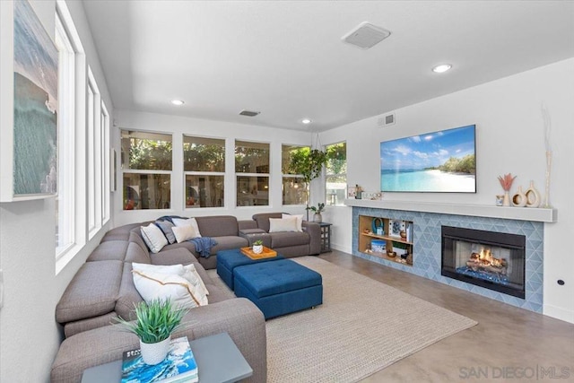 living room featuring a tile fireplace and concrete floors