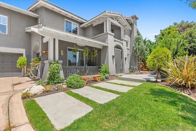 rear view of property featuring a garage, a yard, and a porch