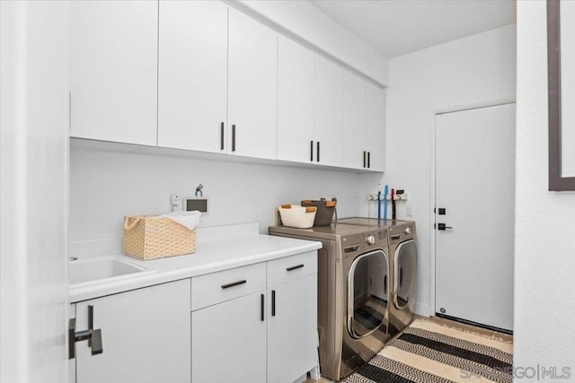 clothes washing area with cabinets, sink, and washing machine and dryer