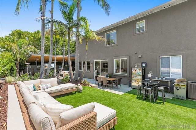 back of property with an outdoor living space, a patio area, and a lawn