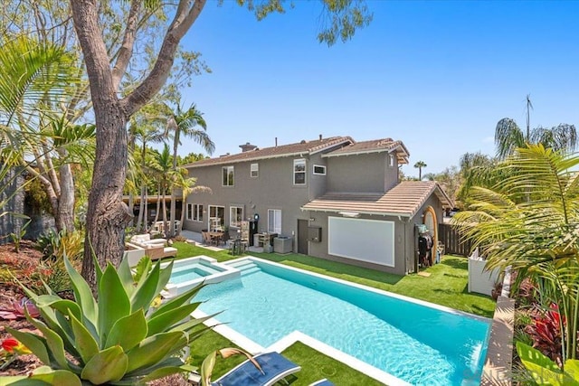 back of property featuring a swimming pool with hot tub, central AC unit, a patio area, and a lawn