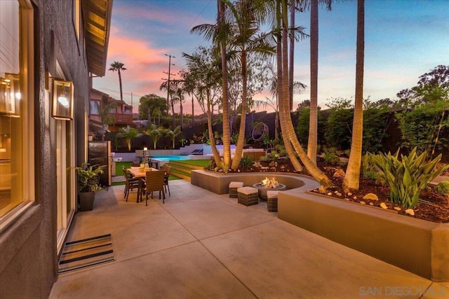 patio terrace at dusk featuring an outdoor fire pit