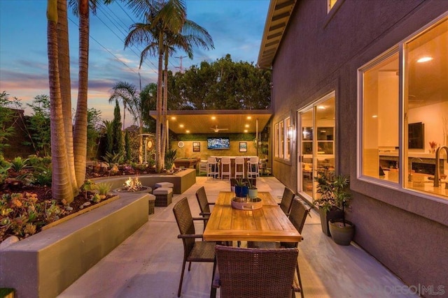 patio terrace at dusk with a bar and a fire pit