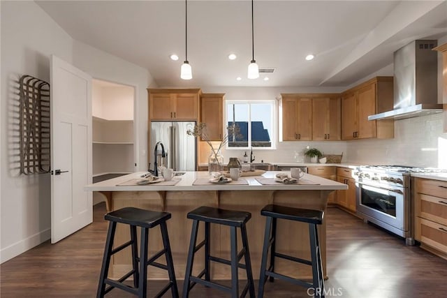 kitchen with high end appliances, an island with sink, and wall chimney exhaust hood