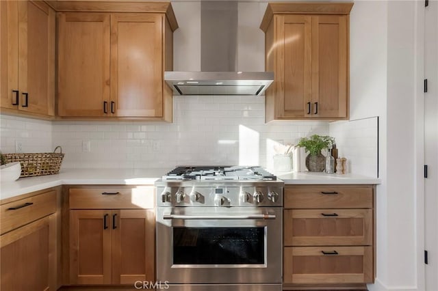 kitchen featuring high end stainless steel range oven, tasteful backsplash, and wall chimney range hood