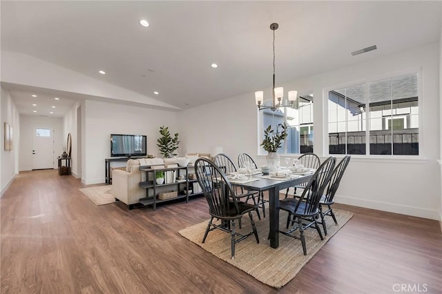 dining space with vaulted ceiling, a wealth of natural light, a notable chandelier, and dark hardwood / wood-style flooring