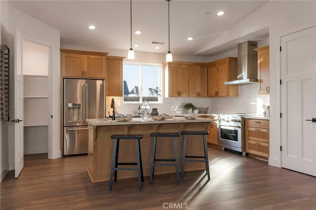 kitchen with a kitchen island, decorative light fixtures, decorative backsplash, high end appliances, and wall chimney range hood