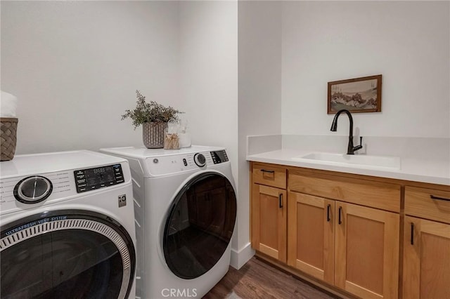 laundry room featuring dark hardwood / wood-style flooring, sink, washing machine and dryer, and cabinets