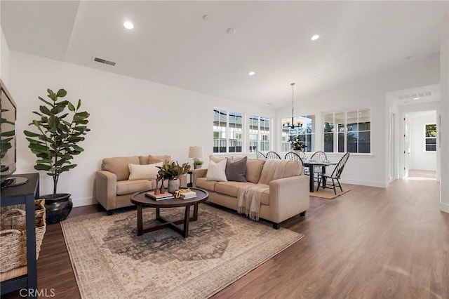 living room with vaulted ceiling, a healthy amount of sunlight, hardwood / wood-style floors, and a notable chandelier