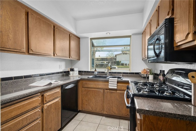 kitchen featuring sink, light tile patterned floors, black appliances, and dark stone counters