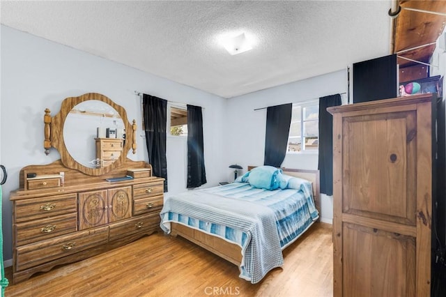 bedroom with a textured ceiling and light wood-type flooring