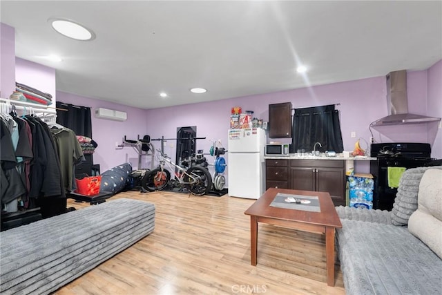 living room featuring a wall mounted air conditioner, light hardwood / wood-style flooring, and sink