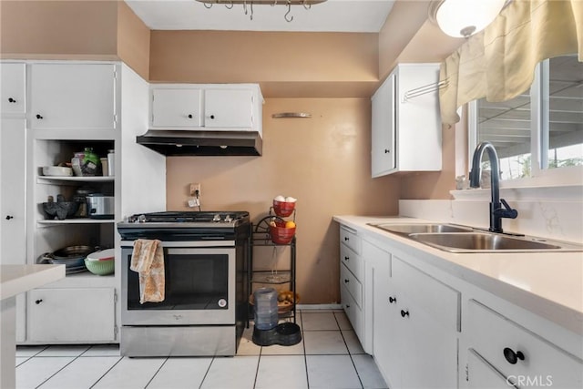 kitchen featuring gas range, sink, light tile patterned floors, and white cabinets