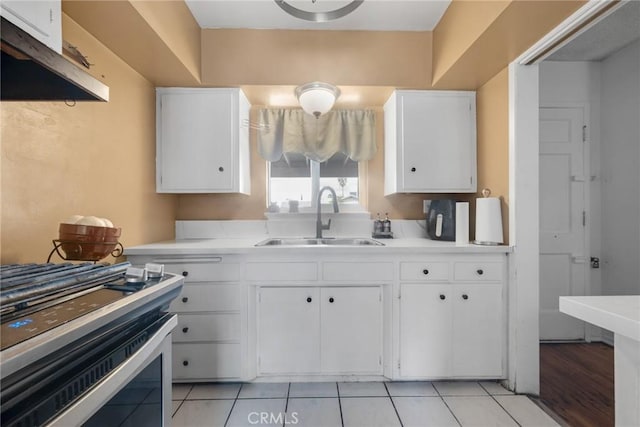 kitchen featuring white cabinetry, stainless steel range oven, sink, and light tile patterned floors