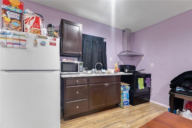 kitchen with black range with gas stovetop, dark brown cabinets, wall chimney exhaust hood, and white fridge