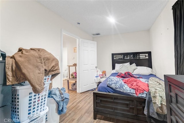 bedroom with a textured ceiling and light hardwood / wood-style floors