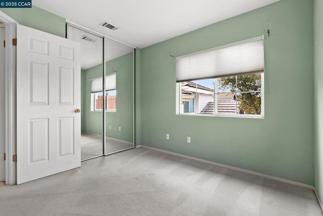 unfurnished bedroom with light carpet and a closet