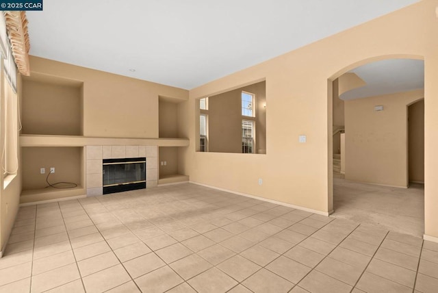 unfurnished living room with a tile fireplace and light tile patterned flooring