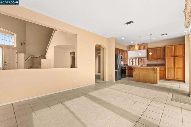 kitchen with a kitchen island, pendant lighting, sink, light tile patterned floors, and stainless steel appliances