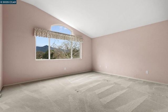 unfurnished room with light colored carpet, lofted ceiling, and a mountain view