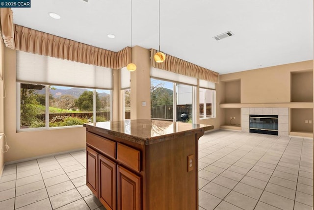 kitchen featuring dark stone countertops, hanging light fixtures, a wealth of natural light, and light tile patterned flooring