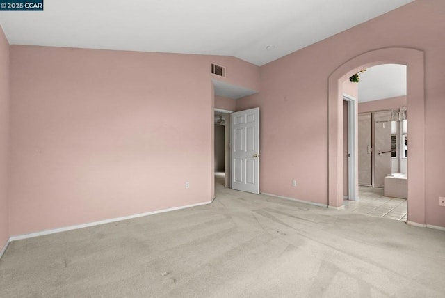 carpeted spare room featuring vaulted ceiling