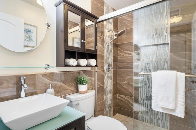 bathroom with vanity, tile walls, toilet, and walk in shower