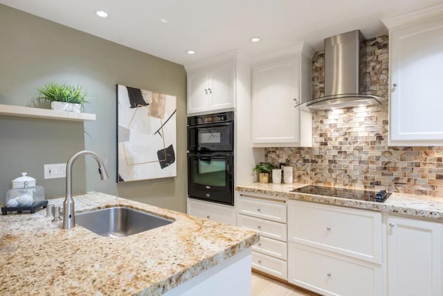 kitchen featuring sink, black appliances, white cabinets, and wall chimney exhaust hood