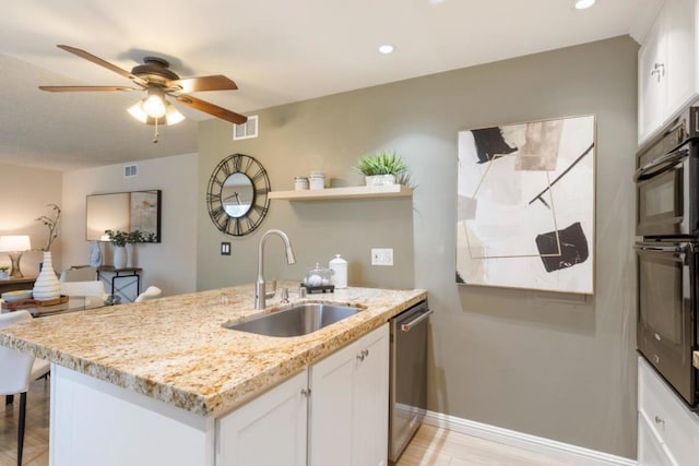 kitchen featuring light stone counters, stainless steel dishwasher, sink, and white cabinets