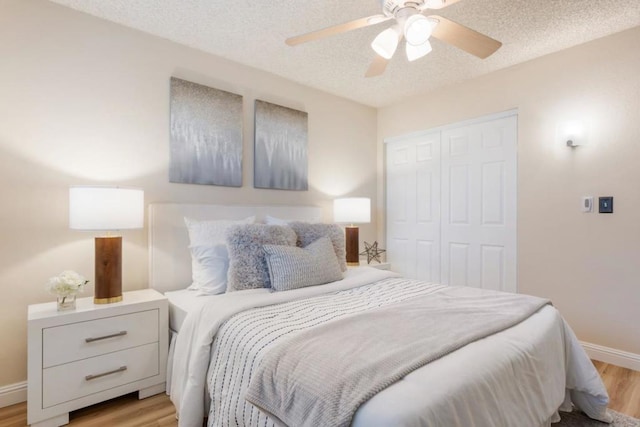 bedroom featuring ceiling fan, a textured ceiling, light hardwood / wood-style floors, and a closet