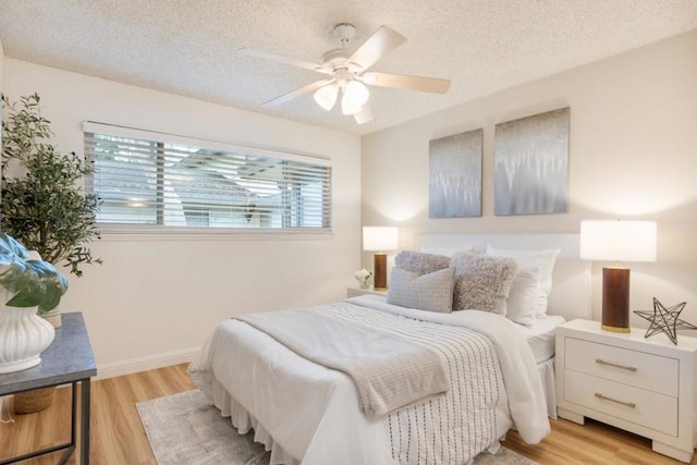 bedroom featuring ceiling fan, a textured ceiling, and light hardwood / wood-style floors