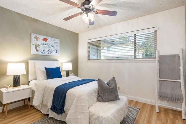 bedroom with ceiling fan, a textured ceiling, and light wood-type flooring