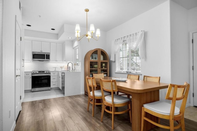 dining room featuring a chandelier, sink, and light wood-type flooring